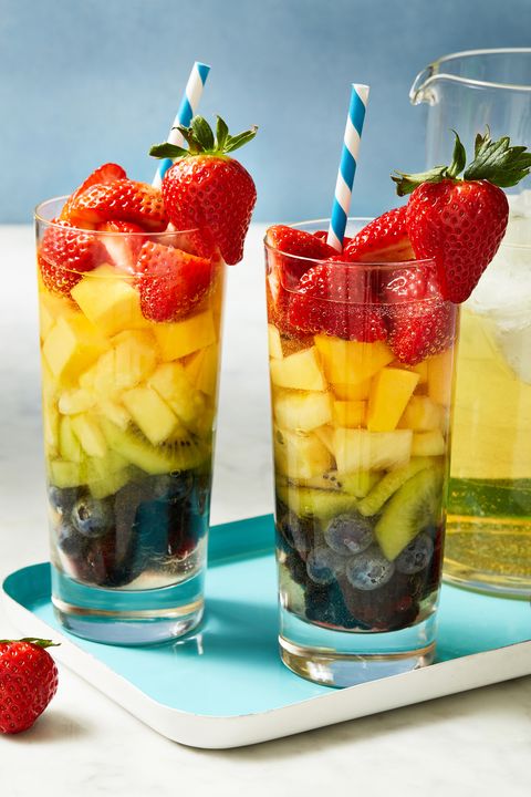two glasses of fruit layered sangria on a teal tray with a pitcher of sangria