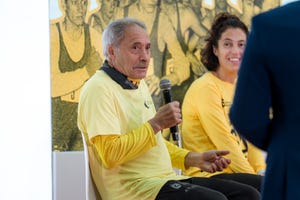 a panel discussion with participants wearing yellow shirts one speaking into a microphone