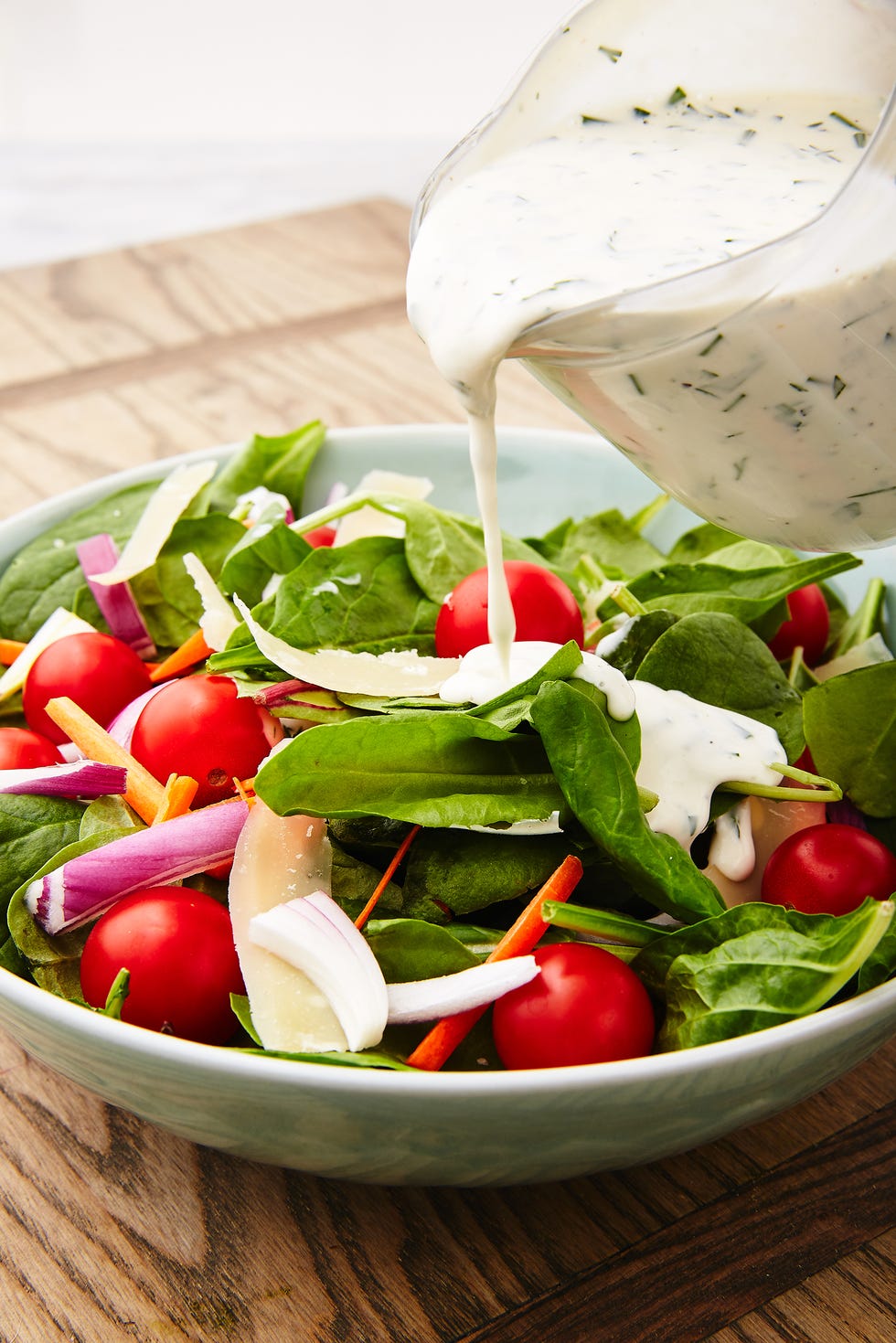 ranch dressing being poured over salad