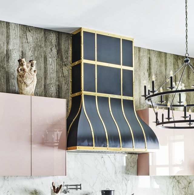 black and brass range hood with pink cabinets