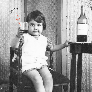 vintage photograph of a young girl cheers ing to the camera with wine