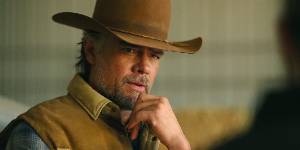 a man wearing a cowboy hat and vest is in a contemplative pose likely engaged in a conversation