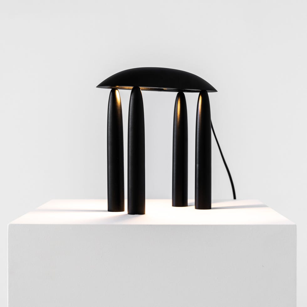 a sleek, modern lamp features a rounded top and four elongated, cylindrical legs