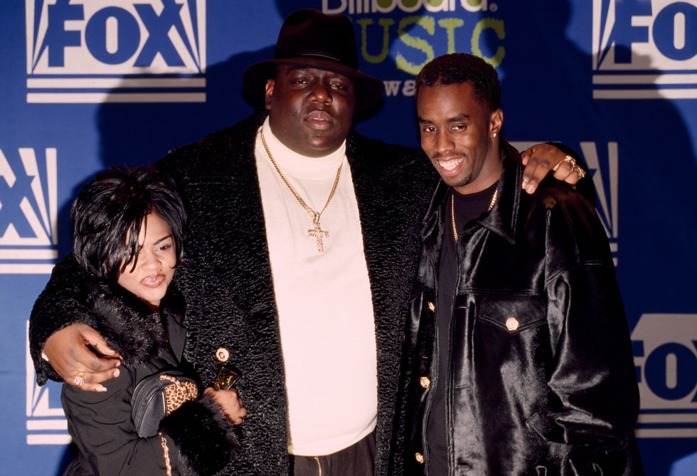 lil kim, notorious big, and sean puffy combs pose for a photo in front of a blue background