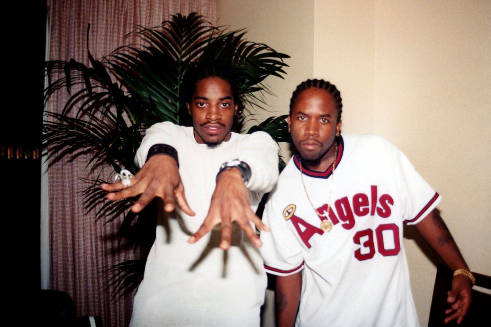 outkast rappers andre 3000 and big boi, both wearing white shirts and posing for the camera inside a hotel room