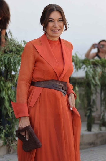 fashionable individual in a flowing orange outfit with a brown belt