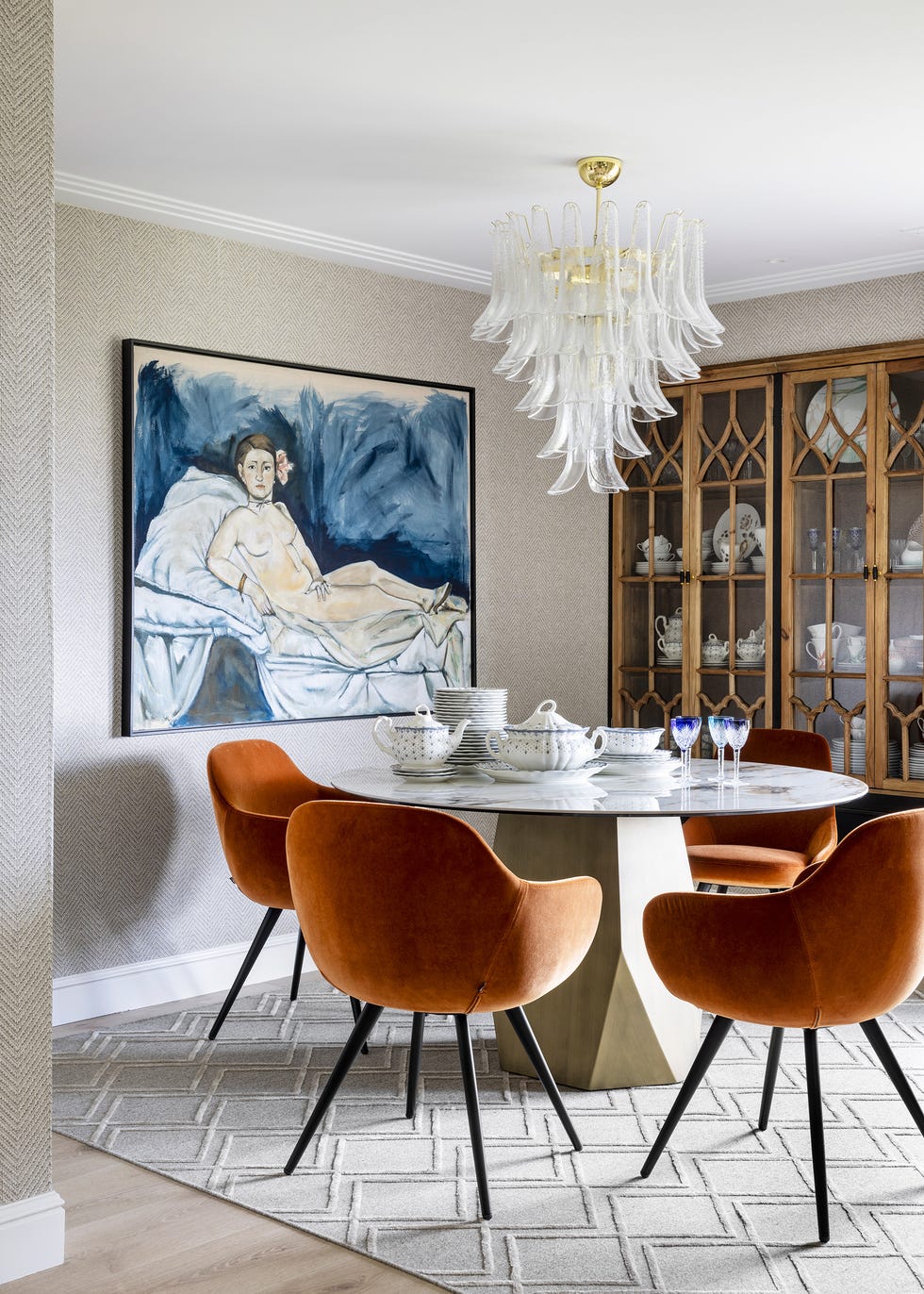 mesa de comedor con sobre de mármol y sillas de terciopelo naranja