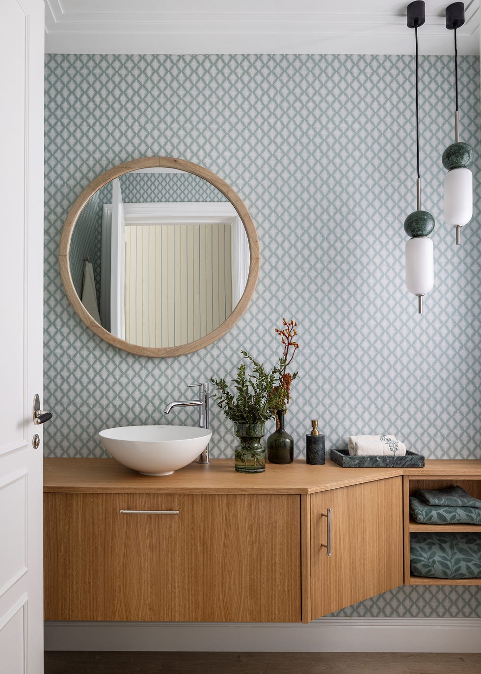 baño con mueble de madera volado y papel pintado con motivos geométricos