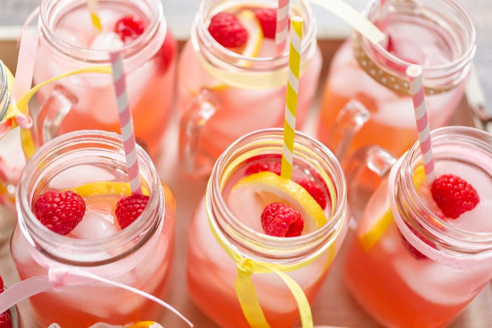 raspberry lemonade garnished with fresh lemon and raspberries in drinking mason jars