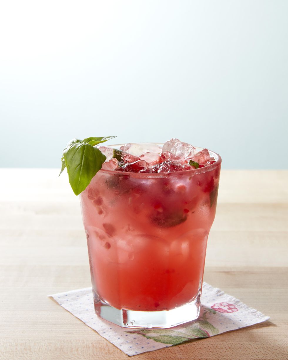 basil raspberry lemonade in a glass with a sprig of fresh basil