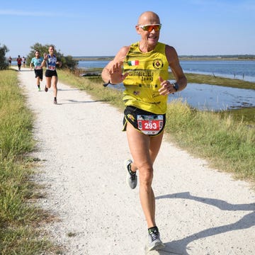 a runner wearing a yellow tank top and black shorts on a path along a water body a runner wearing a yellow tank top and black shorts on a path along a water body