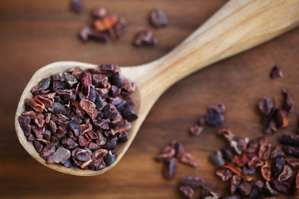 Raw cacao beans in wooden spoon