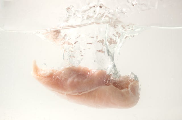 raw chicken breast falling into the water with splash