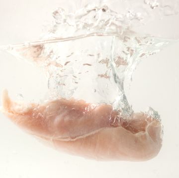 raw chicken breast falling into the water with splash