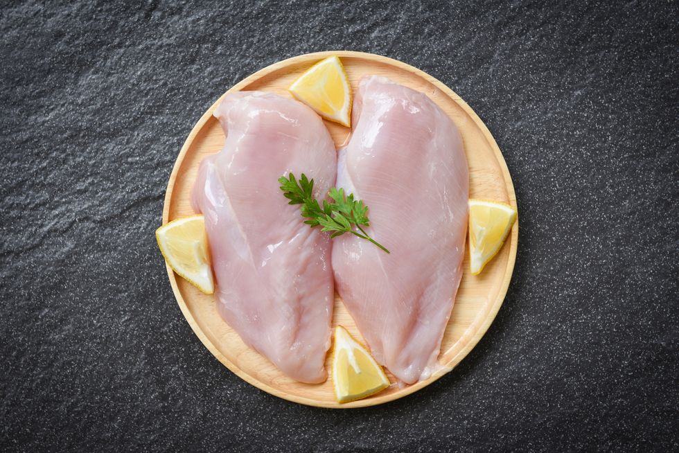 raw chicken breast with herbs and on plate   uncooked chicken meat marinated with lemon for cooking
