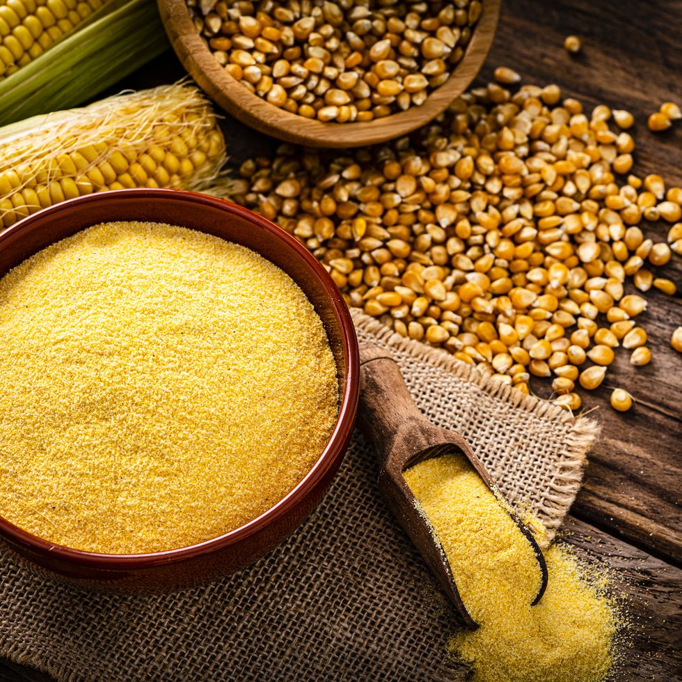 raw corn grits, dried corn and corncobs on rustic table