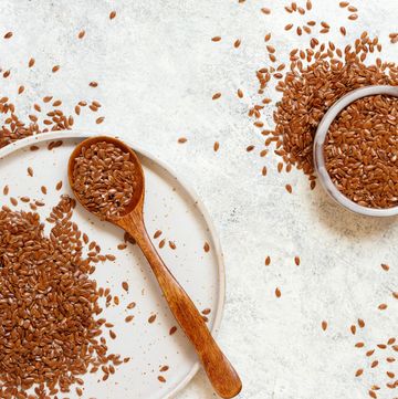 raw flax seeds in a ceramic plate with a wooden spoon