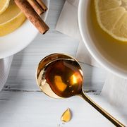 honey on gold spoon next to lemon tea