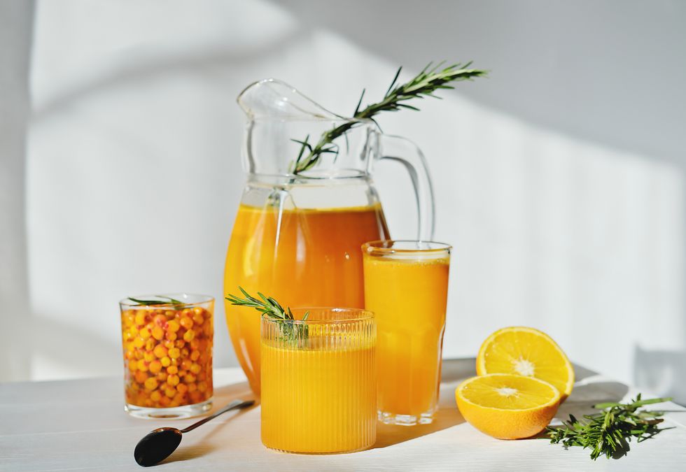 raw sea buckthorn and orange juice in glasses with rosemary antioxidant drinkfor immunity boost in spring vitamin juice for healthy life
