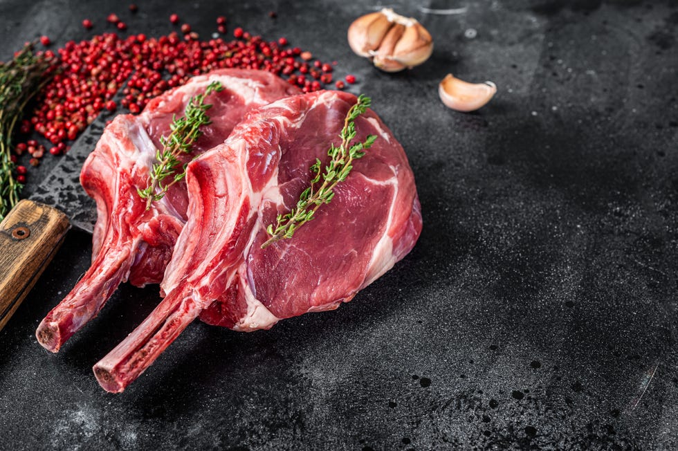 raw tomahawk rib veal steaks on butcher meat cleaver black background top view copy space