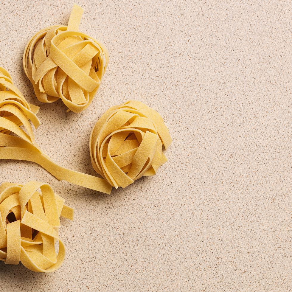 raw uncooked fettuccine pasta nests on beige background