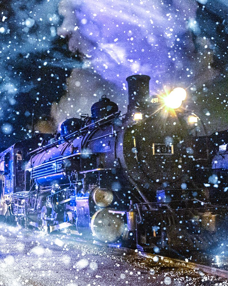 old fashioned steam locomotive seen from the side front, in the snow, at night, with it's headlight on