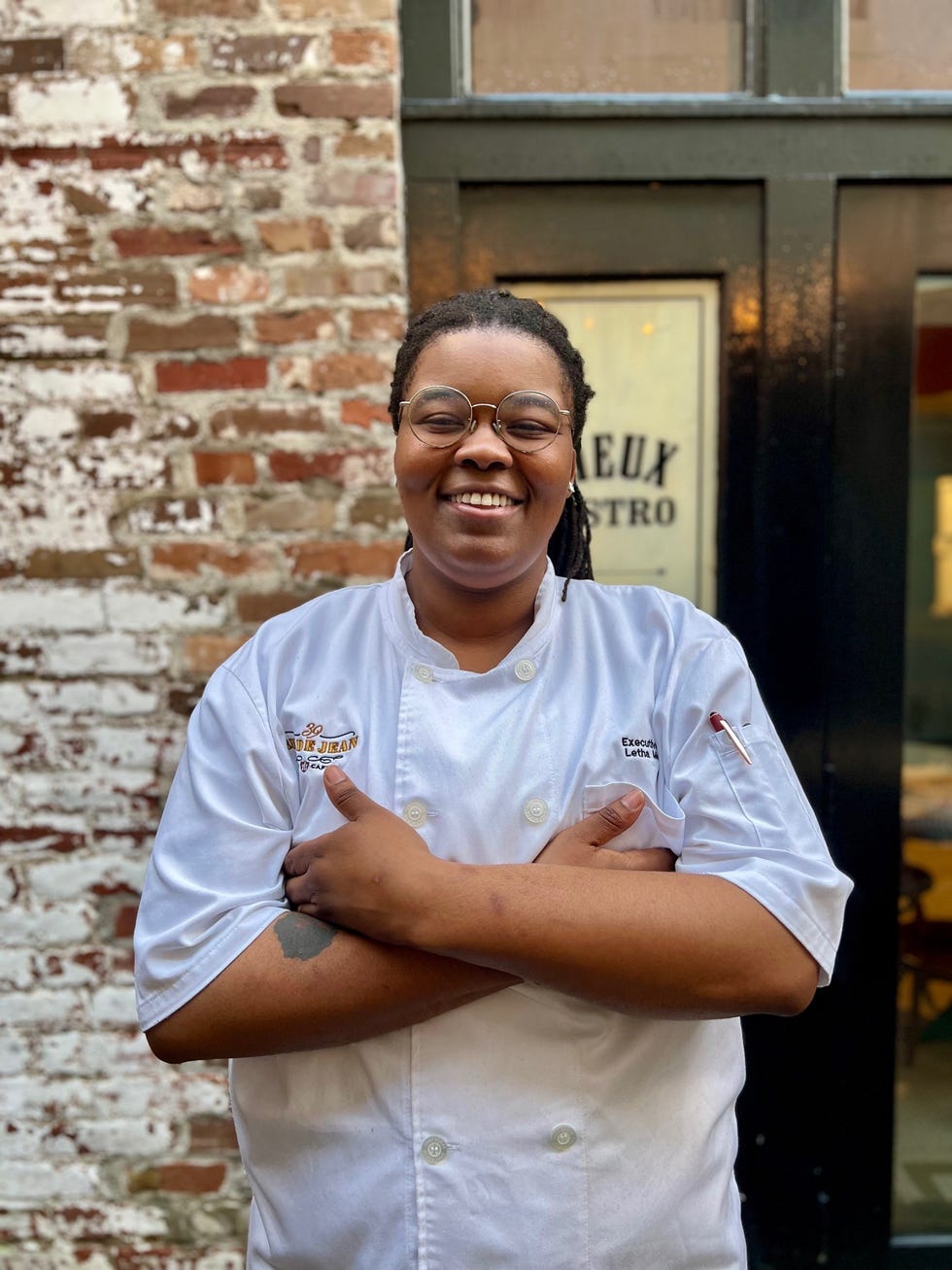 chef standing with arms crossed in front of a restaurant
