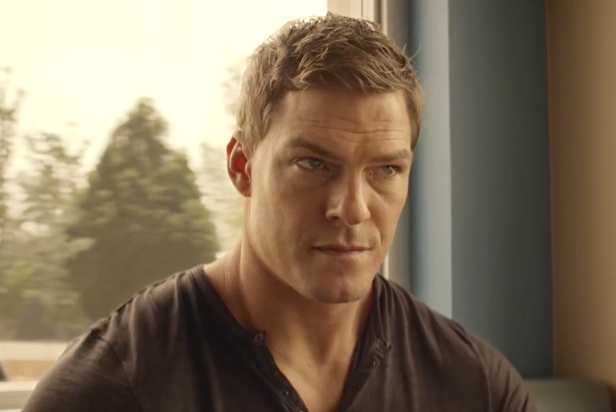 alan ritchson as jack reacher in amazon series reacher, sitting in a cafe wearing a black tshirt