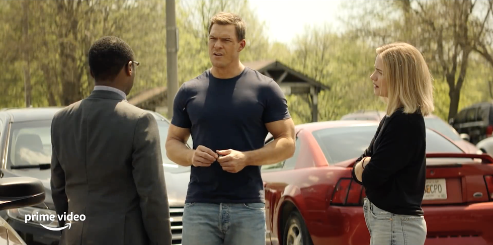 Jack Reacher, Oscar Finley y Roscoe Conklin parados en un estacionamiento hablando en la serie de televisión Reacher