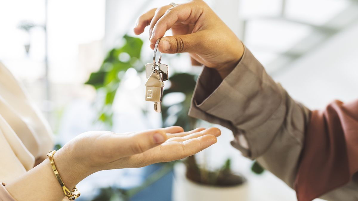 real estate agent giving house key to woman