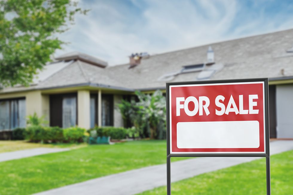 real estate sign in front of a house with a garden for sale