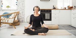 Real woman at home in kitchen doing yoga and meditation