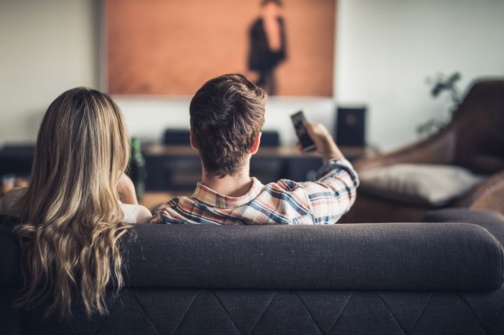 rear view of a couple relaxing on sofa in the living room and watching a movie on tv