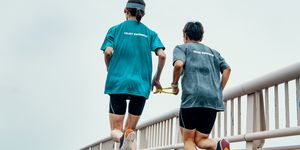 rear view of a visually impaired female triathlete running together with her guide