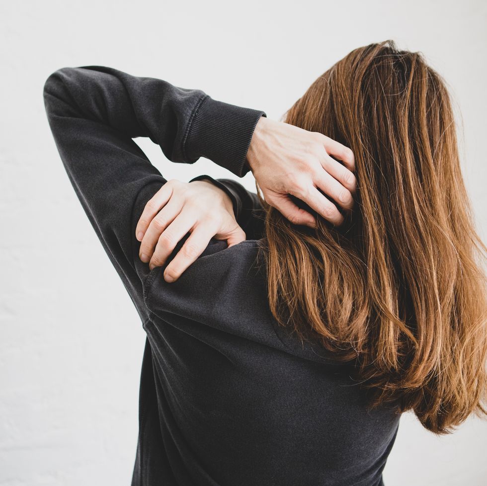rear view of a woman holding her shoulder because of shoulder pain