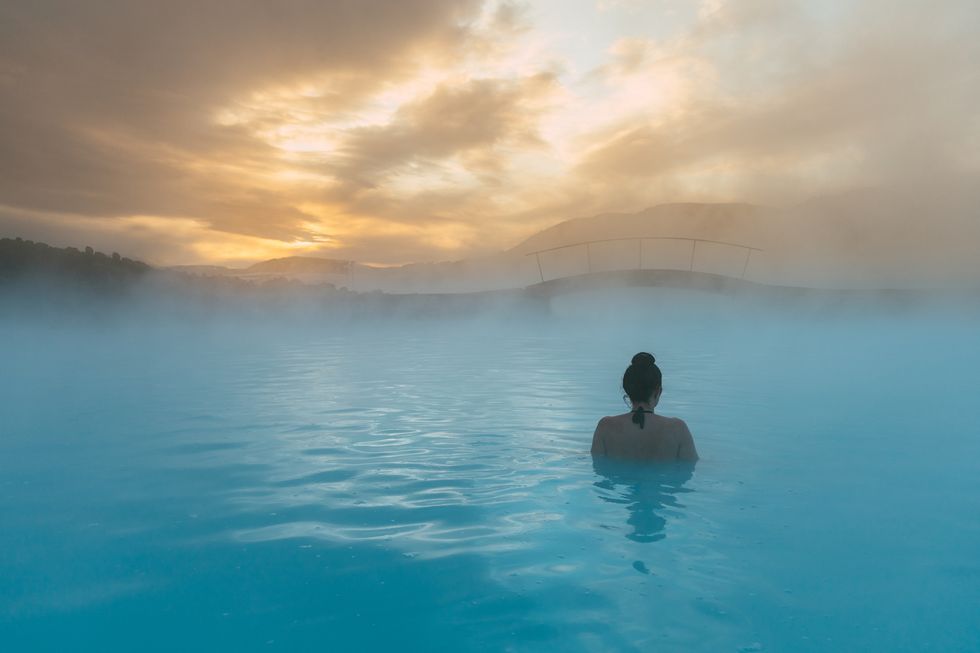 вид сзади на женщину, стоящую в голубой лагуне, исландия