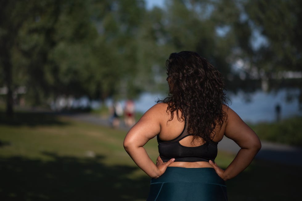 rear view of beautiful young overweight woman standing outdoors in park, exercise concept