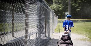 rear view of boy pulling a bag full of baseball equipment off the field