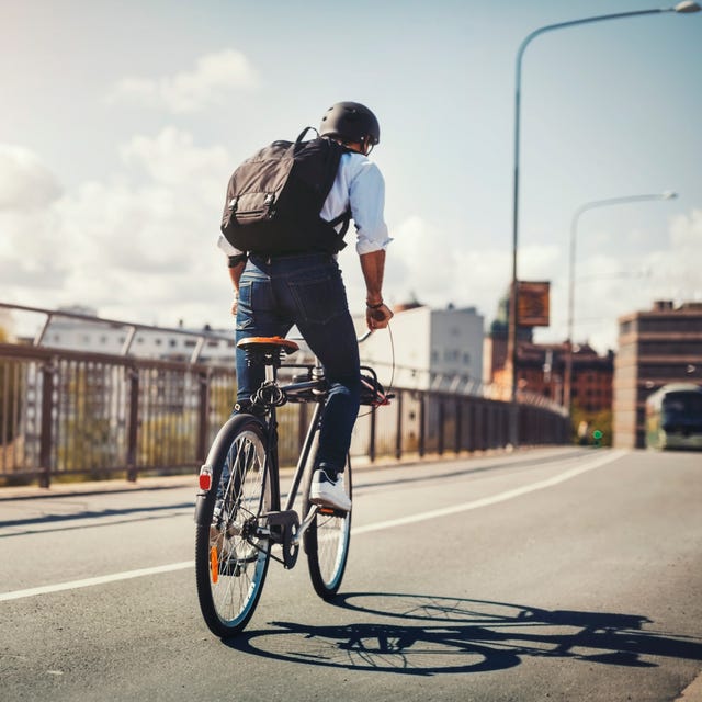 Rear view of businessman riding bicycle on bridge in city