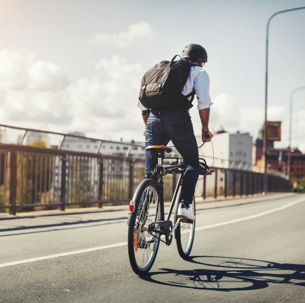 Rear view of businessman riding bicycle on bridge in city