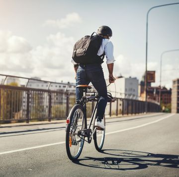 Rear view of businessman riding bicycle on bridge in city