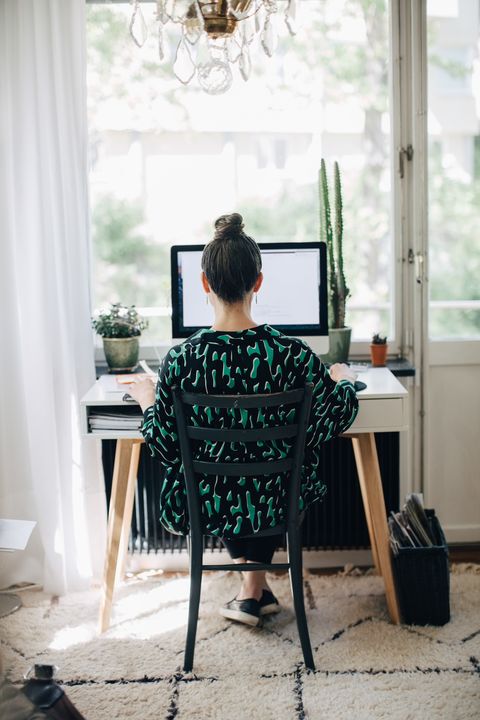 Rear view of businesswoman using computer at desk in home office