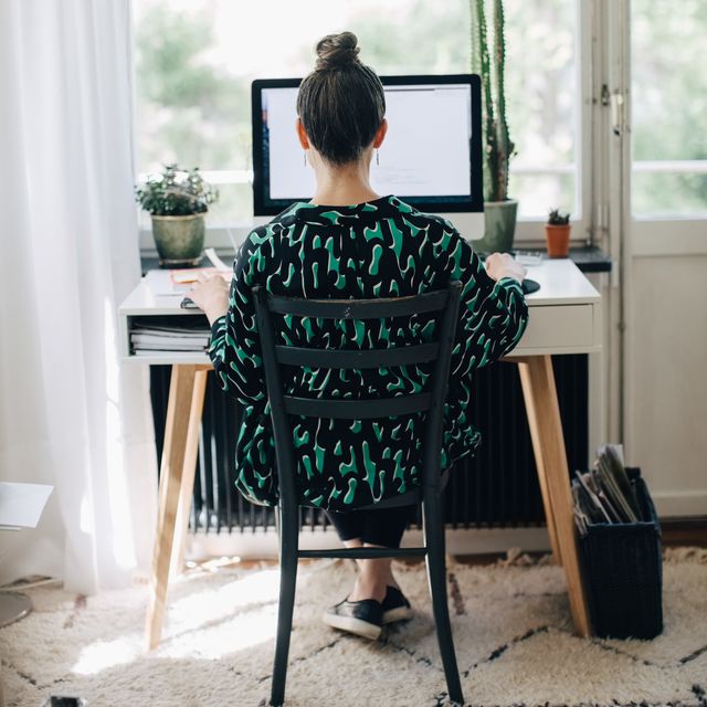 rear view of businesswoman using computer at desk in home office