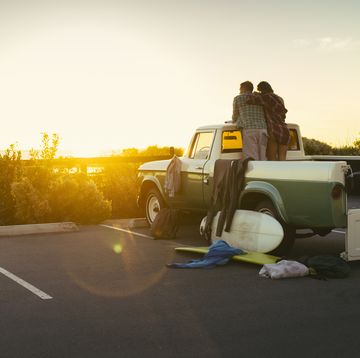 Rear view of couple in back of pickup truck watching sunset at Newport Beach, California, USA