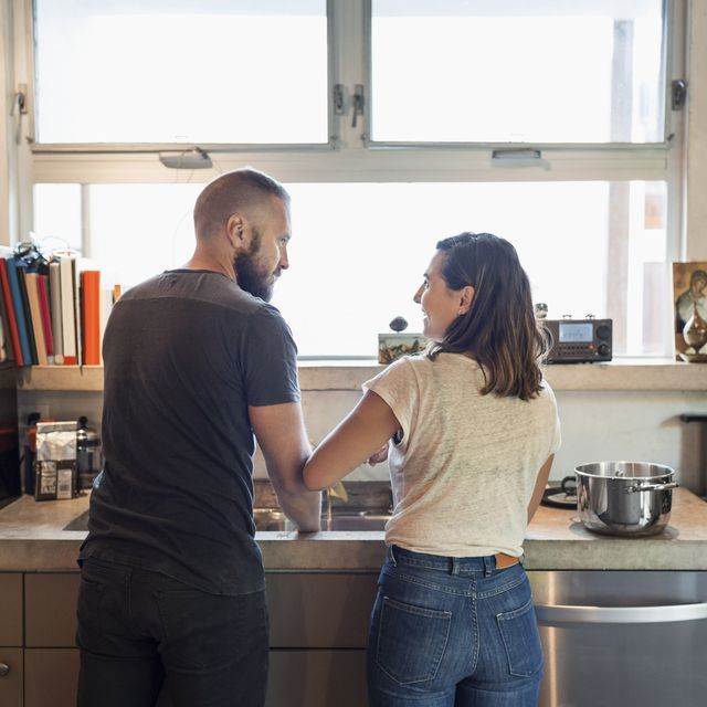 Rear view of couple looking at each other in kitchen
