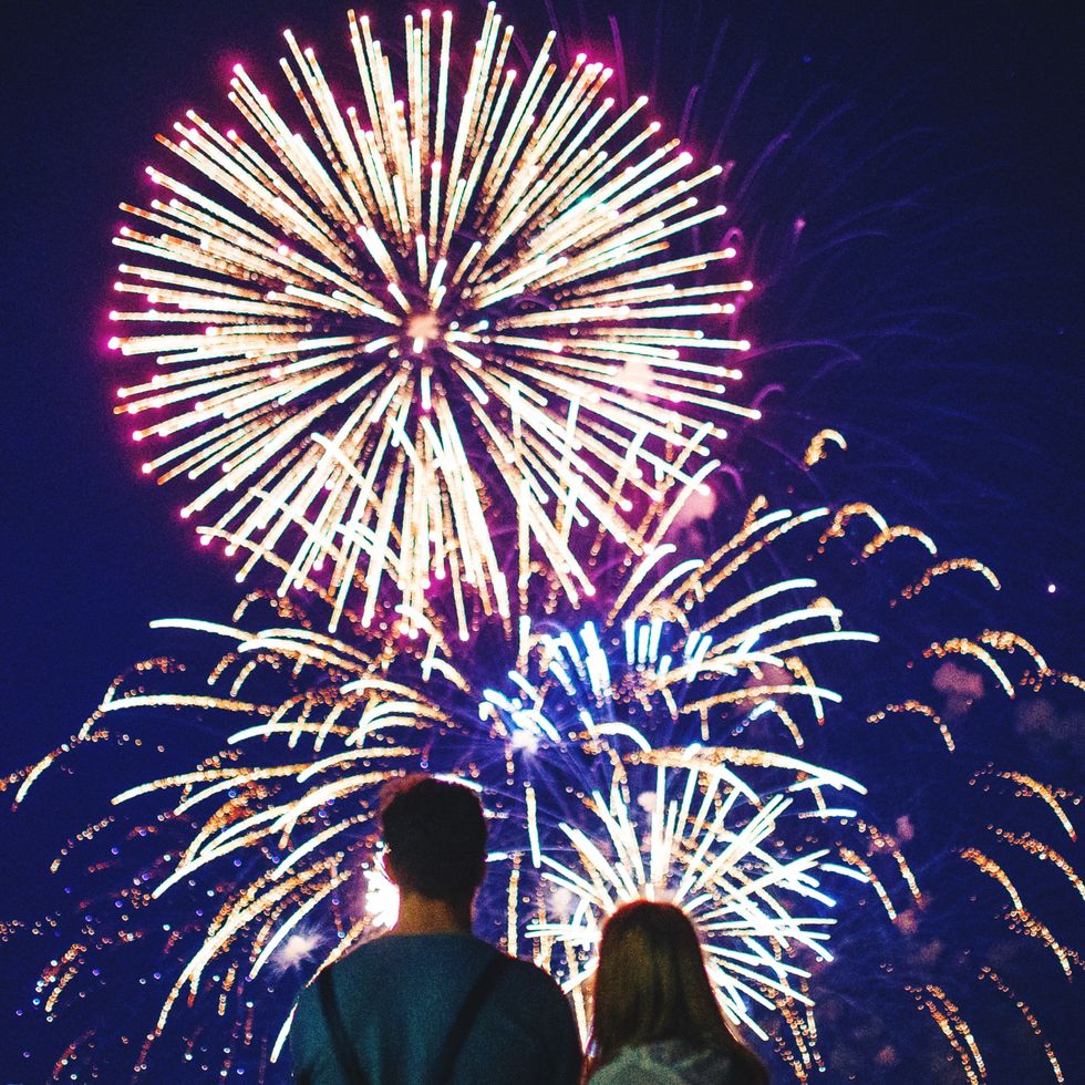 rear view of couple looking at firework display at night