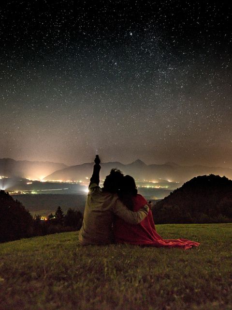 Rear View Of Couple With Flashlight Against Constellation