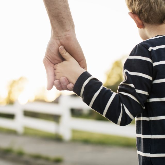 rear view of father and son holding hands while standing outdoors