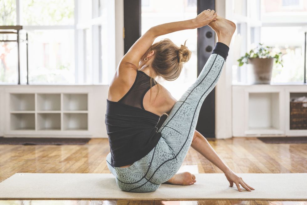 rear view of flexible woman practicing yoga in studio