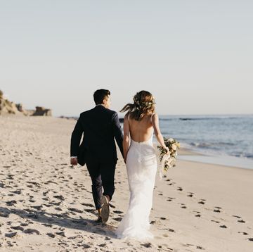 rear view of happy bridal couple running at the beach